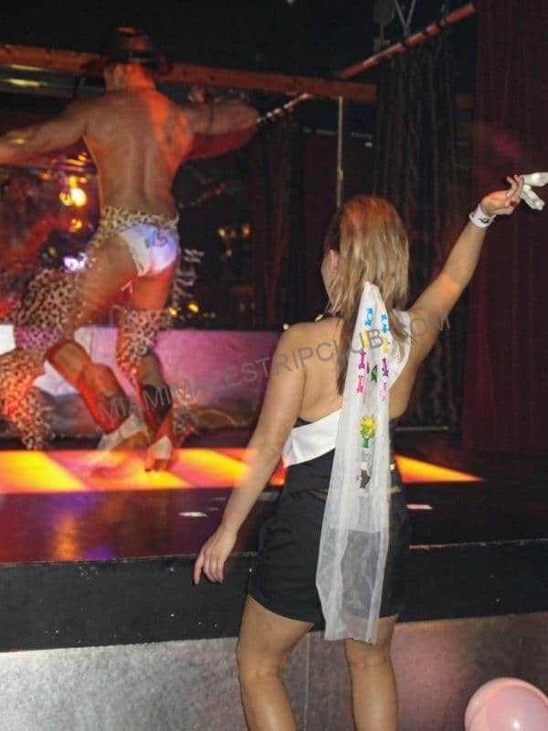 Male stripper performing on stage at a Miami bachelorette party as a guest tips him